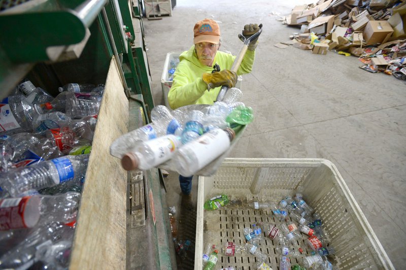 NWA Democrat-Gazette/ANDY SHUPE Mike Gillispie, a recycling worker with Boston Mountain Solid Waste District, uses a shovel Friday to load plastic bottles into a compactor while sorting recyclables at the district's transfer station in Prairie Grove. The holidays usually mean more garbage than usual for households and Fayetteville and its waste partners want to help residents understand what can and cannot be recycled. Not everything that a resident thinks is recyclable actually is, said Brian Pugh, waste reduction coordinator.