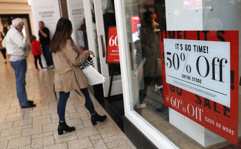 In this Dec. 24, 2018, file photo, discount placards stand in the window of a clothing store as last-minute shoppers finish up their Christmas gift lists at the Cherry Creek Mall in Denver.