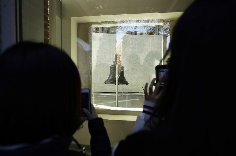 Visitors take photos of the Liberty Bell through a window of its closed display Wednesday at Independence National Historical Park in Philadelphia. 