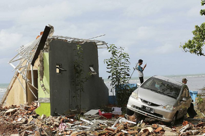 A man photographs tsunami damage Monday in Carita Beach, Indonesia. Saturday’s tsunami struck without warning. 