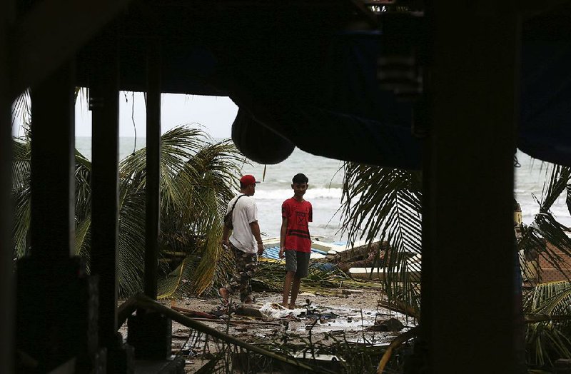 People check out the debris Thursday in a tsunami-ravaged area in Carita, Indonesia. 