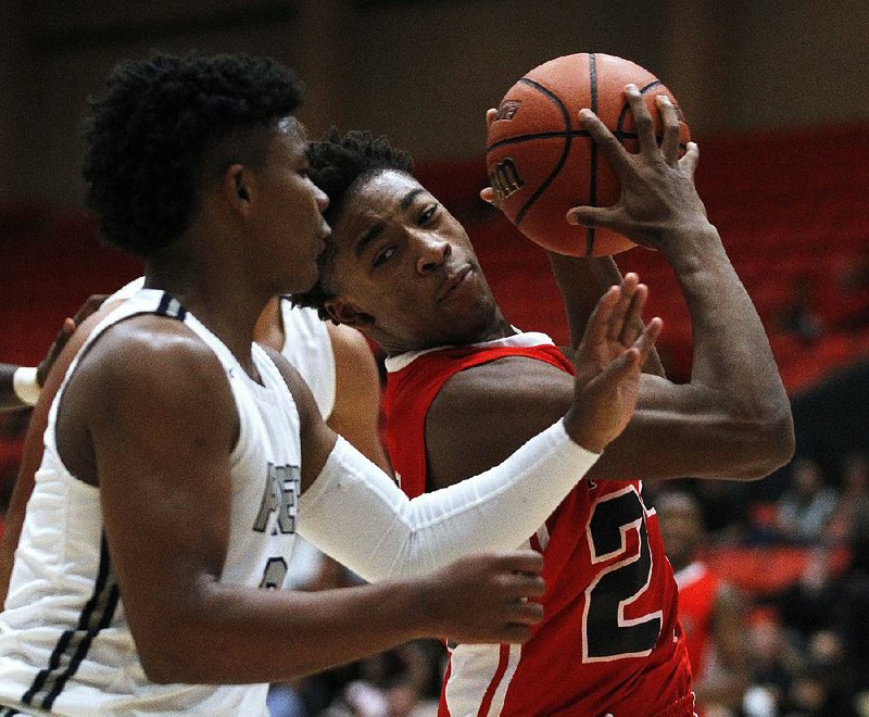 Jacksonville’s Joe Phillips (23) grabs a rebound away from Gulliver Prep’s Gabe Taylor (0) during the first quarter of the Titans’ 72-68 victory in the semifinals of the King Cotton Classic on Friday at the Pine Bluff Convention Center. For more photos, go to arkansasonline.com/galleries. 