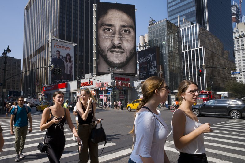 In this Sept. 6 file photo, people walk by a Nike advertisement featuring Colin Kaepernick in New York. In his "Just Do It" spot for Nike that marked the campaign's 30th anniversary in September, the sidelined-by-kneeling NFL quarterback somberly challenged viewers to "believe in something, even if it means sacrificing everything." Some responded with anger, cutting or burning Nike gear and calling for boycotts. (AP Photo/Mark Lennihan, File)

