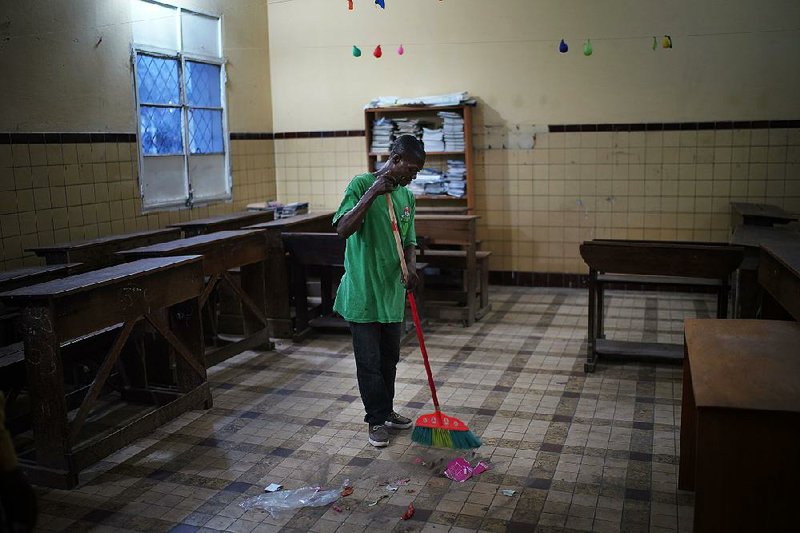 A cleaner in Kinshasa, Congo, prepares a school classroom Saturday to become a polling station for today’s presidential elections. 