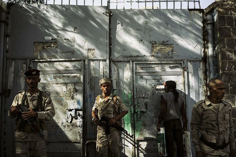 Militiamen guard the entrance of the Najah school in Taiz, Yemen, which serves as Islamist warlord Abu  al-Abbas’ militia  headquarters. 