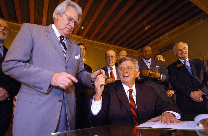 Then-Gov. Mike Beebe hands then state-Sen. Bobby Glover the pen he used on March 18, 2009, to sign a bill sponsored by Glover reducing the grocery sales tax to 2 percent. The tax dropped to 1.5 percent in 2011, and will be lowered to 0.125 percent starting Tuesday. “It will finish my promise,” Beebe said in a recent interview. 