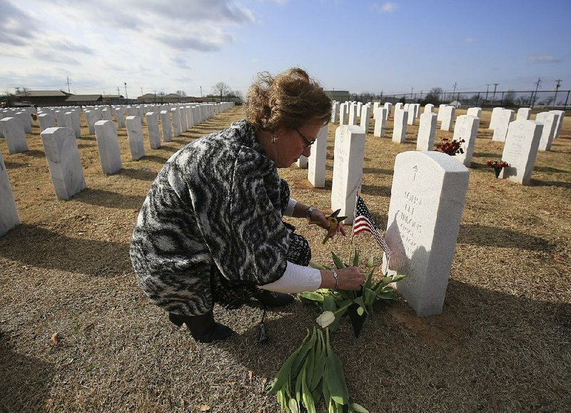 Elly Gibbons puts flowers and a flag on the grave of her husband, Air Force Chief Master Sgt. John Gibbons, at Fort Smith National Cemetery in March. Gibbons and other surviving spouses of veterans are trying to get Congress to repeal a law that blocks some annuity payments. Gibbons says she watches Congress year after year “totally ignore this issue.” 