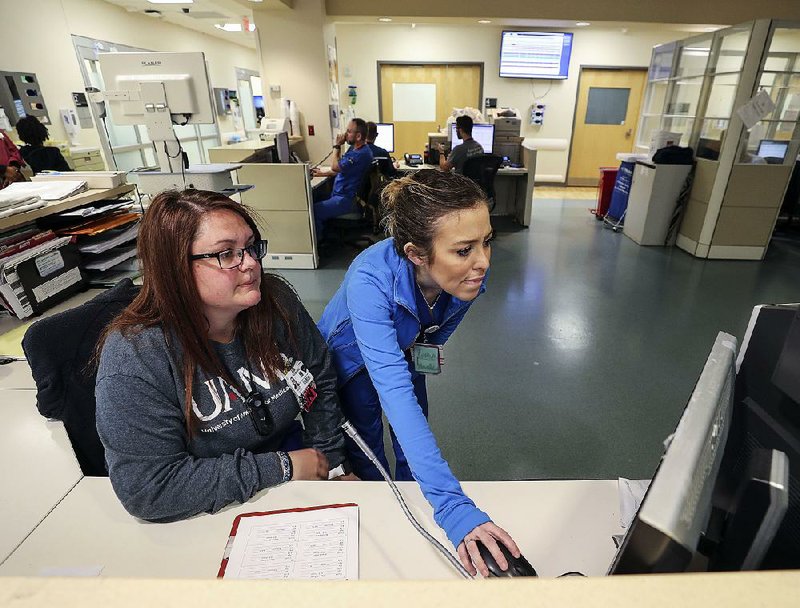 Ashley Ruiz (right) and fellow trauma nurse Catherine Bussy check on a patient’s status earlier this month in the trauma center at the University of Arkansas for Medical Sciences in Little Rock.