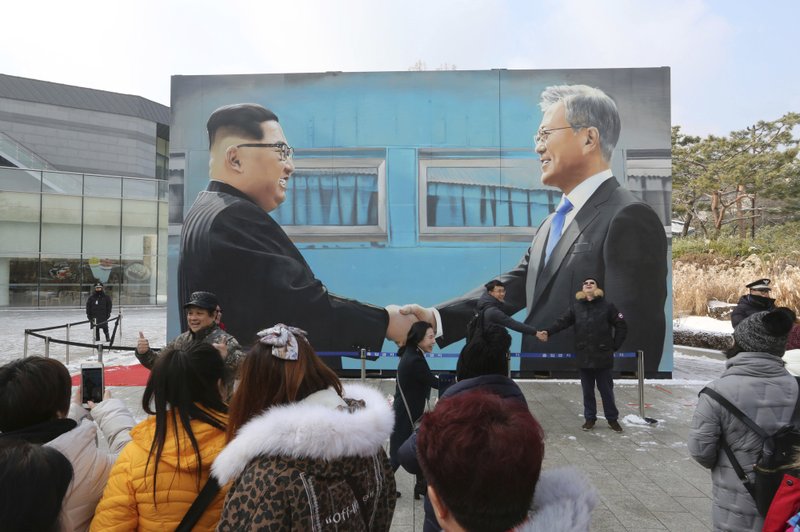 FILE - In this Dec. 13, 2018, file photo, people take pictures of an image of North Korean leader Kim Jong Un, left, and South Korean President Moon Jae-in displayed at a park near the presidential Blue House in Seoul, South Korea. South Korea says Sunday, Dec. 30, 2018, North Korean leader Kim Jong Un has sent a letter to South Korean President Moon Jae-in calling for more talks between the leaders in the new year. (AP Photo/Ahn Young-joon, File)