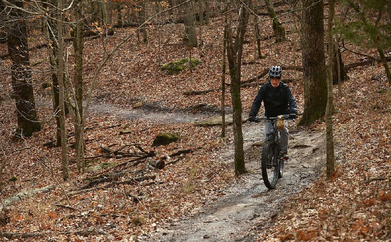 Terry Rodocker of Bella Vista rides his mountain bike Thursday on a trail at Kessler Mountain Region- al Park in Fayetteville. The Fayetteville Natural Heritage Association this year completed its $300,000 commitment to preserving Kessler Mountain.  