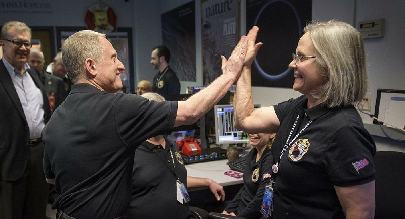 Principal investigator Alan Stern of the Southwest Research Institute in Boulder, Colo., gives a high-five Tuesday in Laurel, Md., to mission operations manager Alice Bowman of the Johns Hopkins University Applied Physics Laboratory after the team received signals from the New Horizons spacecraft that it is healthy and collecting data. 