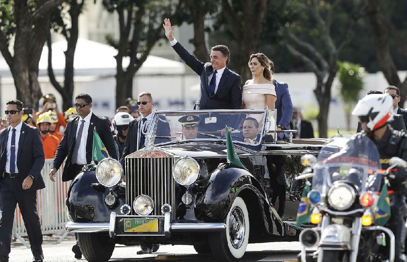Accompanied Tuesday by first lady Michelle Bolsonaro, Brazil’s President Jair Bolsonaro waves after his swearing-in ceremony in Brasilia. 