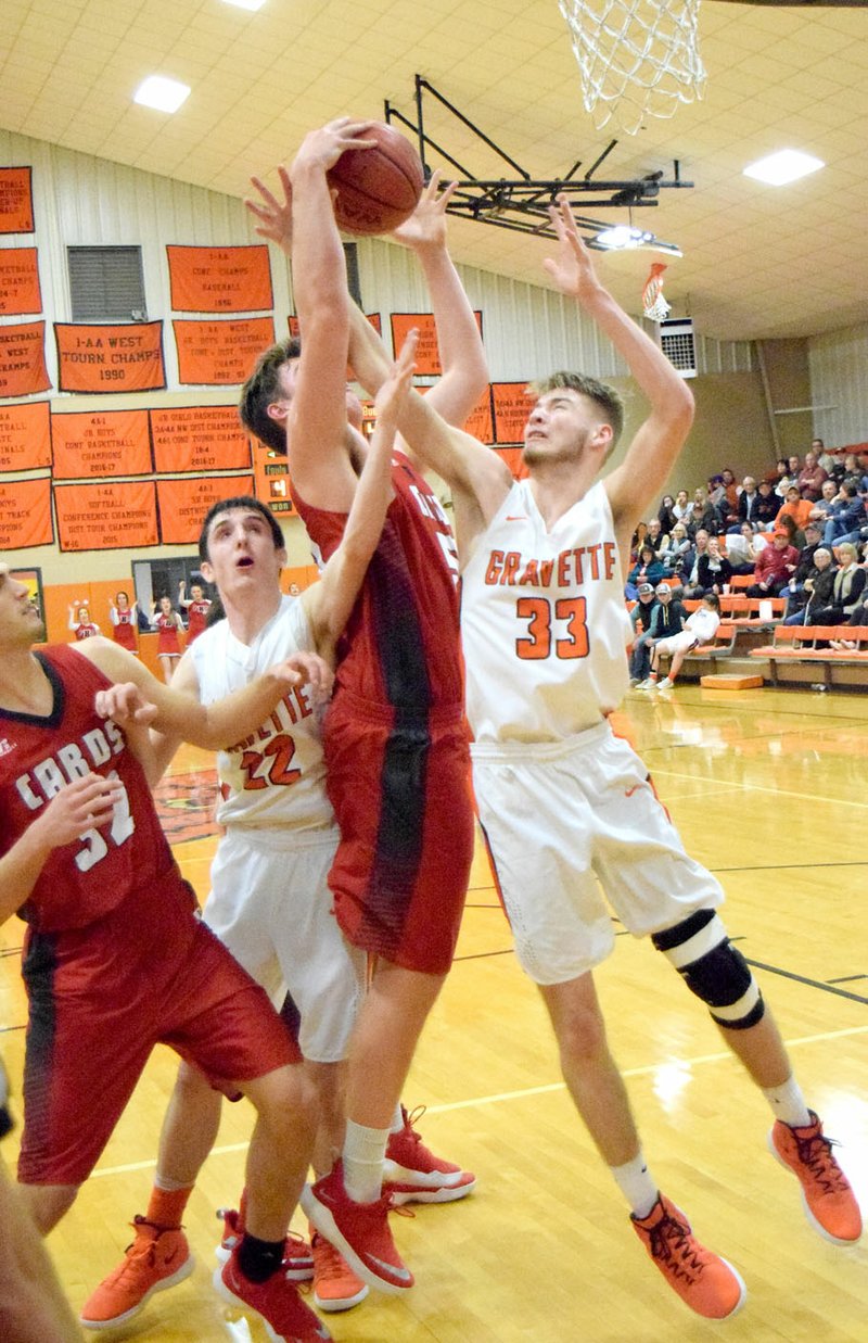 Westside Eagle Observer/MIKE ECKELS Brayden Trembly (Lions 33) fights with Austin Shelley (center) over a rebound during the Gravette-Farmington varsity basketball contest Dec. 21 at the competition gym in Gravette. Farmington edged out Gravette by one point for the win.