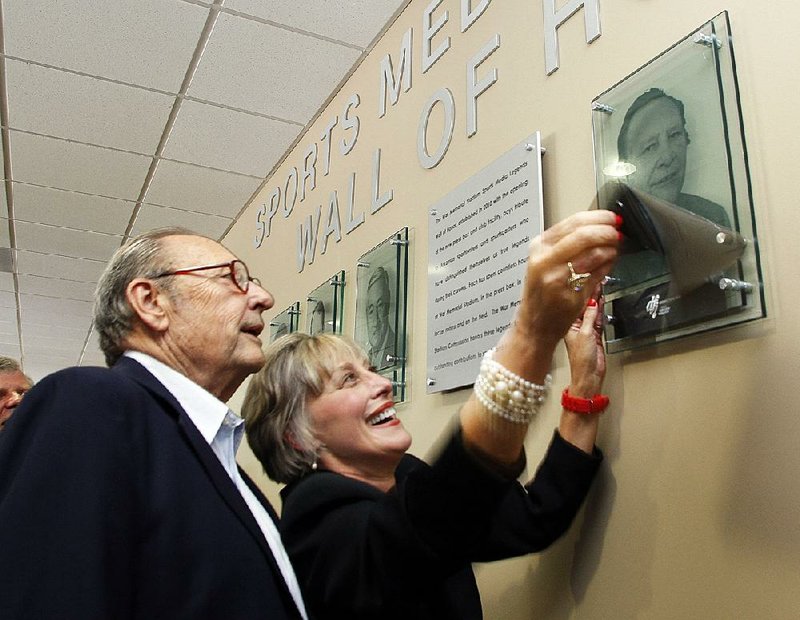 Former Arkansas Democrat-Gazette and Arkansas Gazette sports writer Jim Bailey (left) and Brenda Scisson admire Bailey’s picture during a ceremony adding him to a sports members Wall of Fame in the War Memorial Stadium press box in 2010. Bailey, 86, died in his home Wednesday evening. 