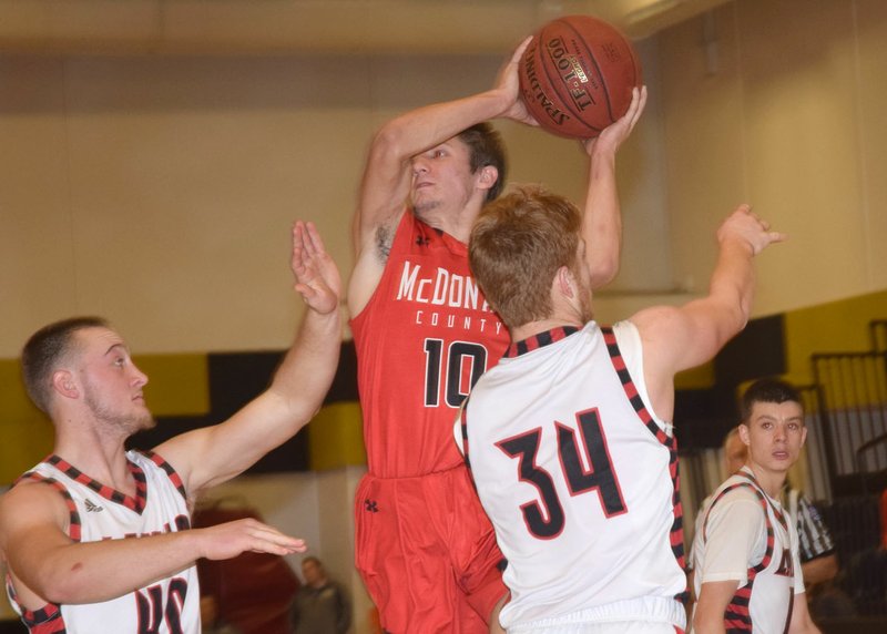 RICK PECK/SPECIAL TO MCDONALD COUNTY PRESS McDonald County's Koby McAlister looks to pass while being defended by Lamar's Travis Bailey (40) and Case Tucker (34) during the Mustangs' 76-58 loss on Dec. 29 in the fifth place game of the 64th Neosho Holiday Classic.