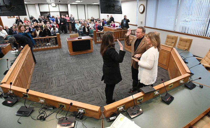 NWA Democrat-Gazette/J.T. WAMPLER Fourth Judicial Circuit Judge Stacey Zimmerman (left) swears in Washington County sheriff Tim Helder on Wednesday at the Washington County Courthouse in Fayetteville. Helder's wife, Holly Helder, holds a Bible for the ceremony.