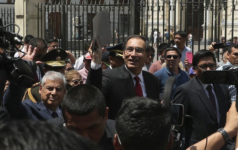 Peru's President Martin Vizcarra holds up a folder as he waves next to next to Prime Minister Cesar Villanueva, left, as they leave the government palace for Congress where he plans to urge legislators to declare an emergency at the attorney general's office, in Lima, Peru, Wednesday, Jan. 2, 2019.  (AP Photo/Martin Mejia)