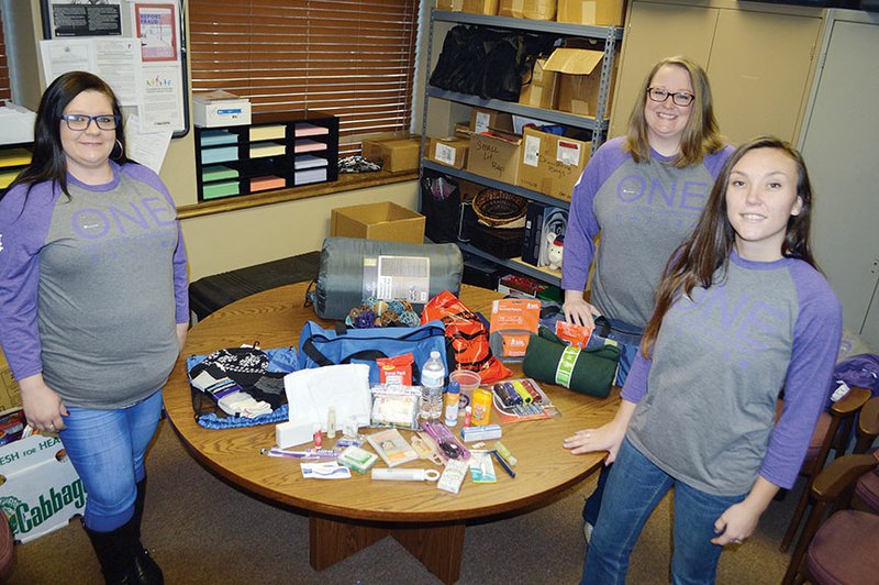 Standing with items that will be given away at the third annual Project Homeless Connect, scheduled for 4-7 p.m. Jan. 22 at St. Joseph’s Spiritan Hall, 1115 College Ave. in Conway, are, from left, Jessica Pope, office assistant for the Community Action Program for Central Arkansas; Melissa Allen, community programs director; and Kindale Armstrong, emergency services advocate.