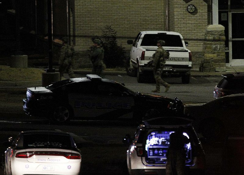 Arkansas State Police troopers walk around the Cleburne County Courthouse in Heber Springs during a standoff Friday night at the sheriff’s office that’s in the building. 