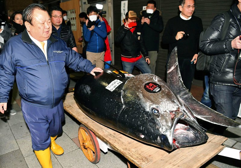 Kiyomura Corp. owner Kiyoshi Kimura, left, stands near the bluefin tuna which he made a wining bid at the annual New Year auction, in Tokyo Saturday, Jan. 5, 2019. The 612-pound (278-kilogram) bluefin tuna sold for a record 333.6 million yen ($3 million) in the first auction of 2019, after Tokyo's famed Tsukiji market was moved to a new site on the city's waterfront. (Koki Sengoku/Kyodo News via AP)