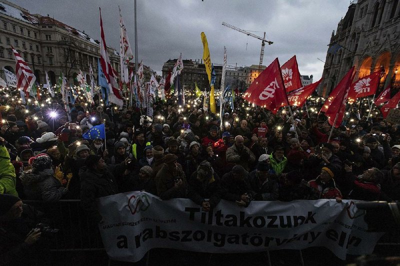 Anti-government demonstrators carry a banner reading “We protest against the slave bill” during a rally Saturday in front of the parliamentary building in Budapest, Hungary. The banner refers to legislation that allows for forced overtime while permitting employers to delay payments to workers. 