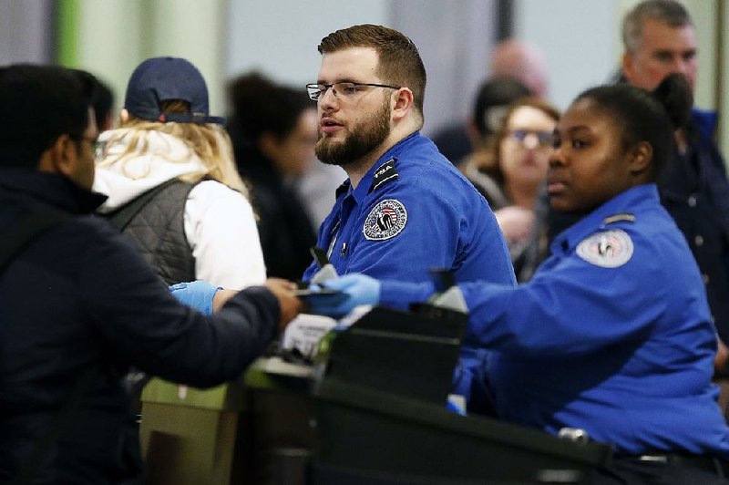 Transportation Security Administration officers move travelers through a checkpoint Saturday at Logan International Airport in Boston. 