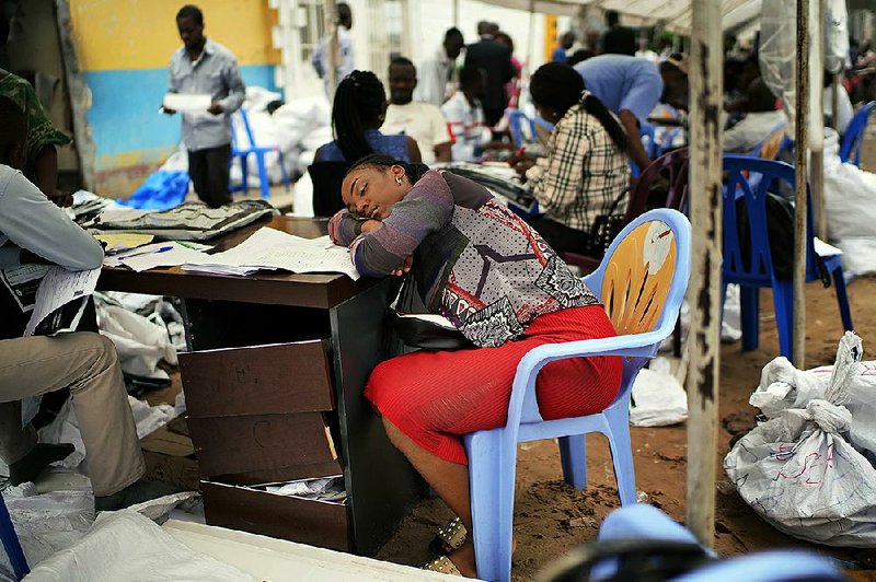 A member of the Congolese electoral commission rests Sunday as votes from the presidential race are tallied at a compilation center in Kinshasa.