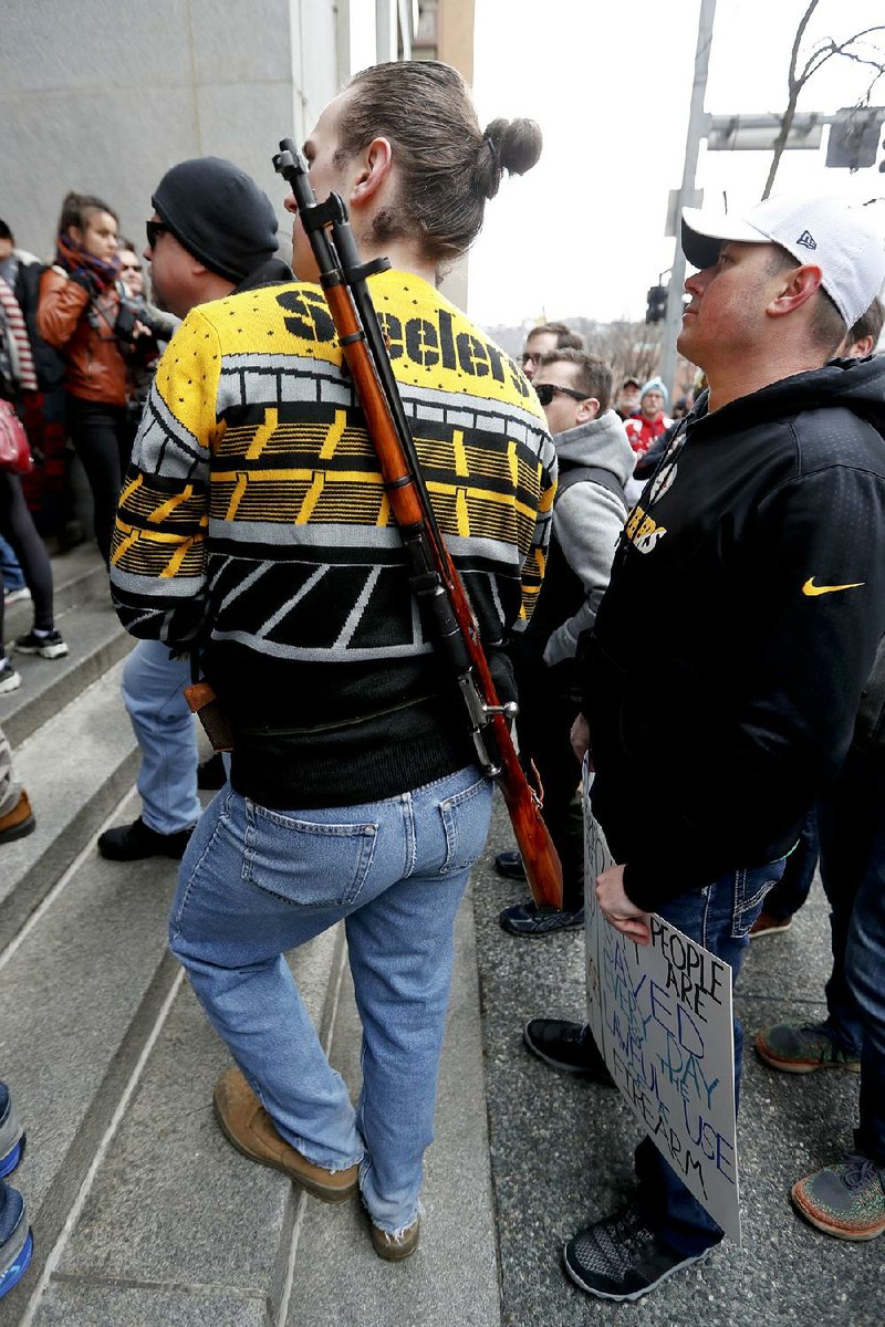 A protester with a bolt-action rifle strapped around his back at- tends a rally Monday, in Pittsburgh. The protesters, many openly carrying guns, gathered in downtown Pittsburgh to rally against the city council’s proposed restrictions and banning of semi-automatic rifles, certain ammunition and firearms accessories within city limits. 