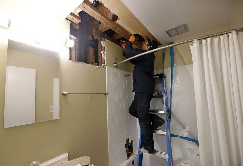 Plumbers work in a bathroom, threading together tub drains in an apartment building in Seattle. U.S. service firms grew at a slower pace in December. 