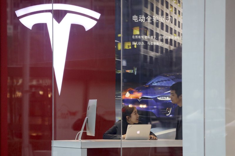 Workers chat in a Tesla store in Beijing, China, Monday, Jan. 7, 2019. Tesla Motors CEO Elon Musk said Monday on Twitter that the automaker is breaking ground for a Shanghai factory and will start production of its Model 3 electric car by the end of the year. (AP Photo/Ng Han Guan)
