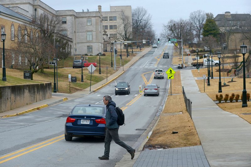 NWA Democrat-Gazette/ANDY SHUPE
A pedestrian crosses Maple Street Thursday, Jan. 3, 2018, on the University of Arkansas campus in Fayetteville. The city of Fayetteville and University of Arkansas are planning to install a two-way bicycle track on Maple Street from the Razorback Greenway near Gregg Avenue to Garland Avenue. Estimated cost on the project is $4 million.