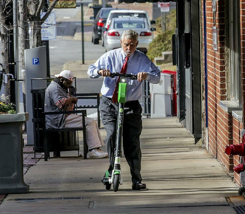 Charles Hicks gets underway on a scooter Tuesday on a sidewalk in the River Market District of Little Rock. Hicks said using a scooter to get from his office in the Stephens Building to the River Market for lunch would be handy. 