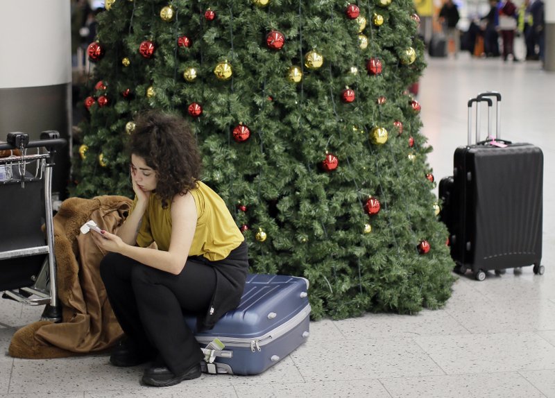 FILE - In this Thursday, Dec. 20, 2018 file photo, a woman waits in the departures area at Gatwick airport, near London, as the airport remains closed after drones were spotted over the airfield last night and this morning. London's Heathrow Airport suspended flight departures as a precaution Tuesday, Jan. 8, 2019 after a reported drone sighting that came just three weeks after a rash of drone sightings shut London's Gatwick Airport. (AP Photo/Tim Ireland, file)