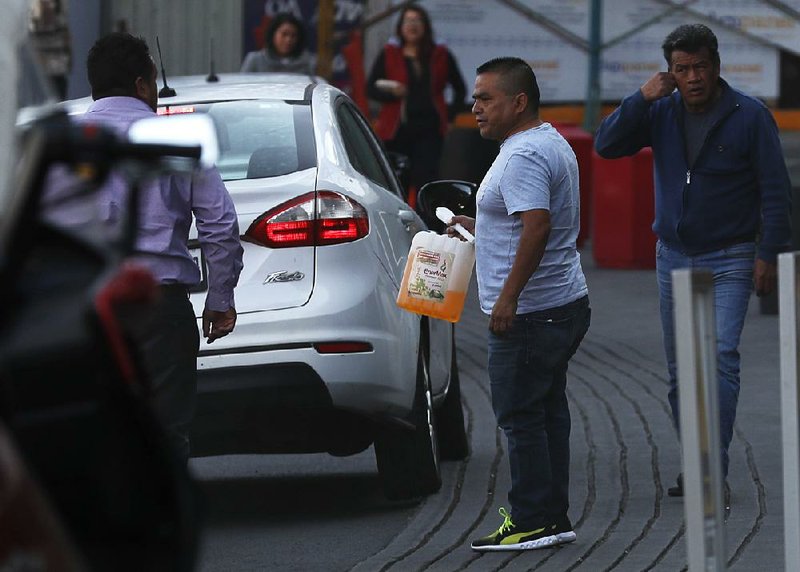 A man with a container joins the line at one of the few gas stations open Tuesday in Mexico City  after the government’s decision to curb pipeline deliveries led to fuel shortages around the country. 