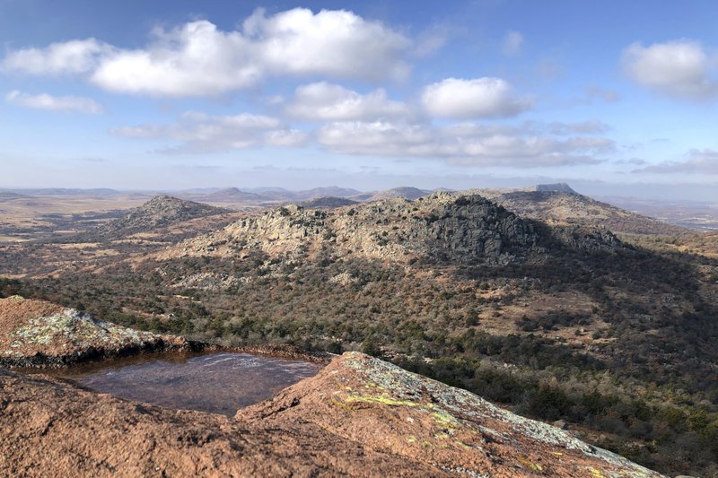 In this Dec. 31, 2018 photo, clouds cast shadows in the Wichita Mountains Wildlife Refuge in Comanche County, Okla. The U.S. Fish and Wildlife Service is directing dozens of wildlife refuges including this one to make sure hunters and others have access despite the government shutdown, according to an email obtained Wednesday by The Associated Press.  (AP Photo/Adam Kealoha Causey)