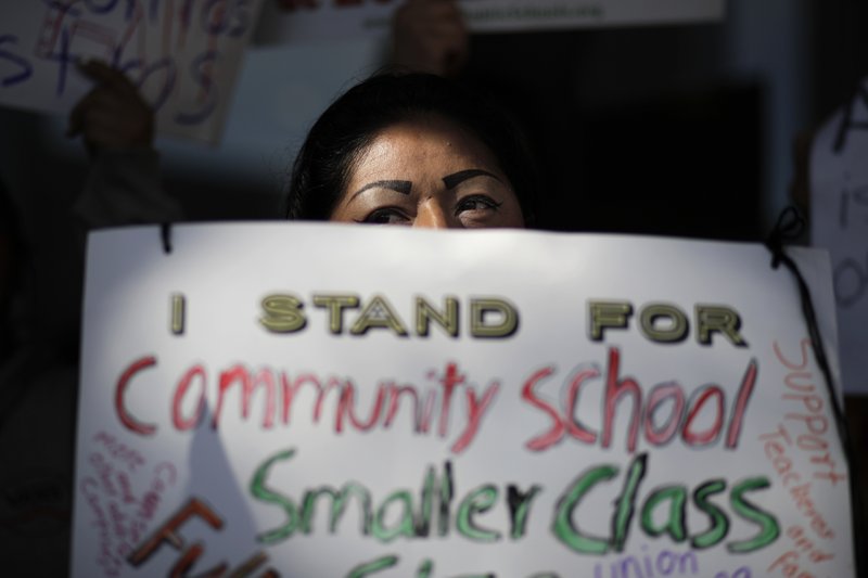 Manuela Panjoj, 42-year-old mother of five children, holds a sign during a news conference outside the Los Angeles Unified School District headquarters Wednesday, Jan. 9, 2019, in Los Angeles, Calif. The union representing teachers in Los Angeles has postponed the start of a possible strike until Monday because of uncertainty over whether a judge would order a delay. (AP Photo/Jae C. Hong)
