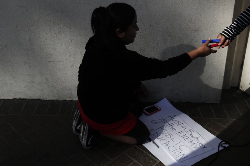 Noemi De La Cruze, whose three children are attending Los Angeles Unified School District schools, makes signs before a news conference outside the LAUSD headquarters Wednesday, Jan. 9, 2019, in Los Angeles, Calif. The union representing teachers in Los Angeles has postponed the start of a possible strike until Monday because of uncertainty over whether a judge would order a delay. (AP Photo/Jae C. Hong)
