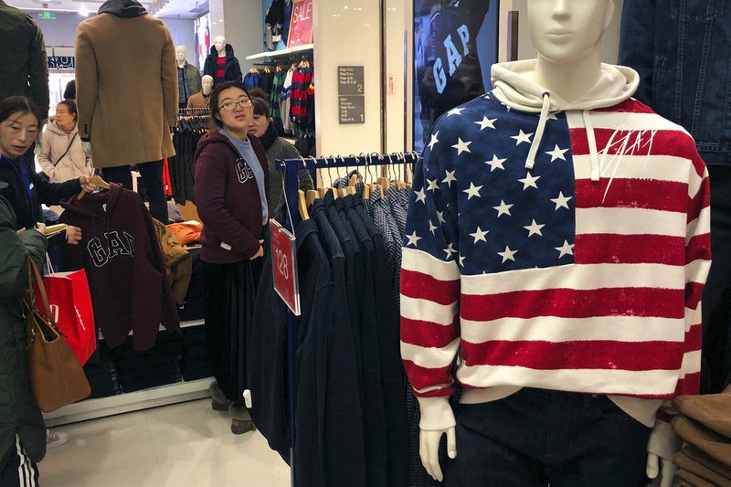 A woman tries out a sweater at a U.S. retailer GAP's flagship store in Beijing, Thursday, Jan. 10, 2019. Uncertainty over the outcome of China-U.S. trade talks is casting a pall over Asian markets as both sides kept quiet about what lies ahead. (AP Photo/Andy Wong)