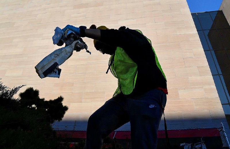 Sarmad Bhatti pulls a handful of trash from a garden area outside the National Air and Space Museum on Sunday. Due to the partial government shutdown, some national parks are overflowing with trash. So the Ahmadiyya Muslim Youth Association volunteered to pick up garbage and empty trash cans on the National Mall. Other teams of young men did cleanup at other national parks across the country. 