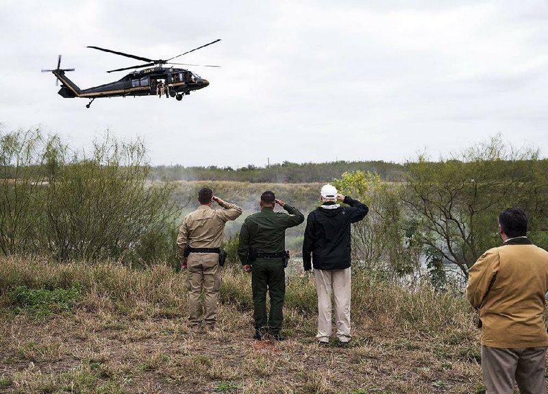 President Donald Trump (right) salutes a U.S. Customs and Border Protection helicopter Thursday as it flies over the Rio Grande during Trump’s visit to the border town of McAllen, Texas. Trump met with Border Patrol officers and heard stories of violent deaths at the hands of people in the country illegally. 