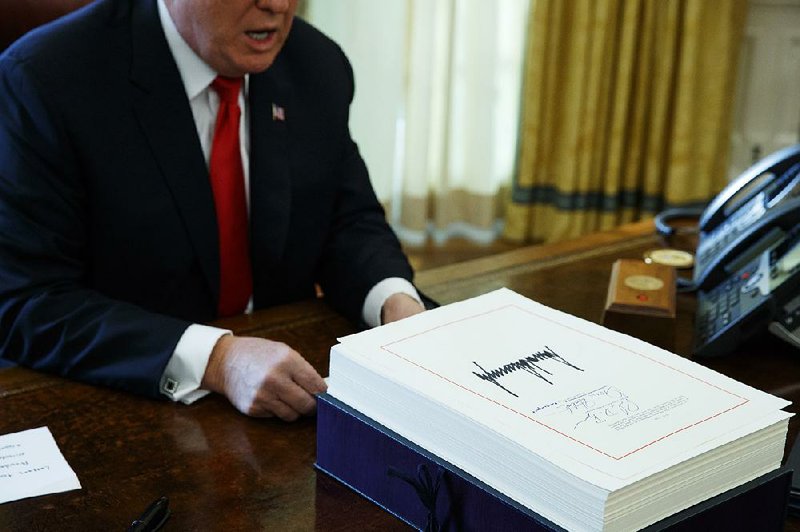 President Donald Trump speaks with reporters after signing the tax bill and continuing resolution to fund the government in the Oval Office of the White House in Washington in December of 2017. 