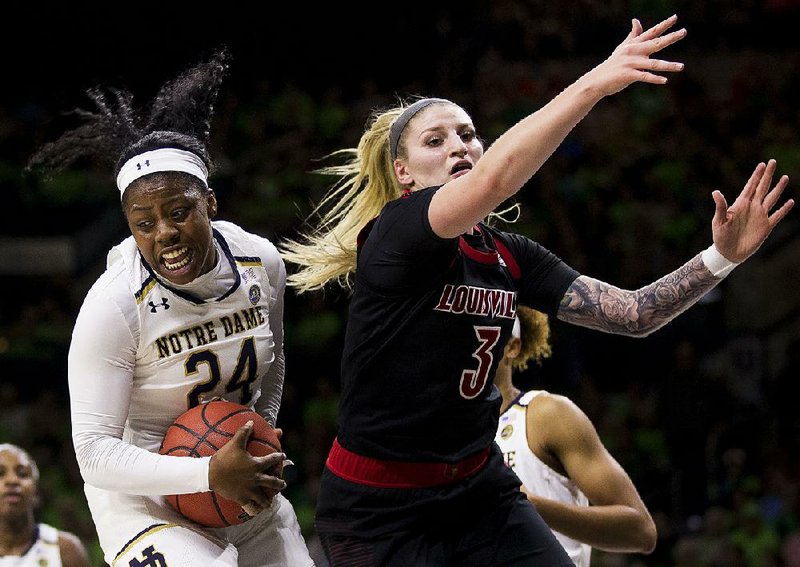 Notre Dame’s Arike Ogunbowale (left) grabs a rebound next to Louisville’s Sam Fuehring during the first half Thursday in South Bend, Ind. Ogunbowale scored 30 points to lead the top-ranked Irish to an 82-68 victory. 