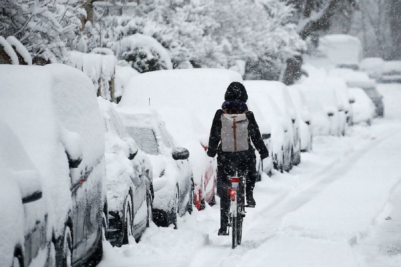 A woman makes her way on a bicycle early Thursday after heavy snowfall in Munich, Germany. 