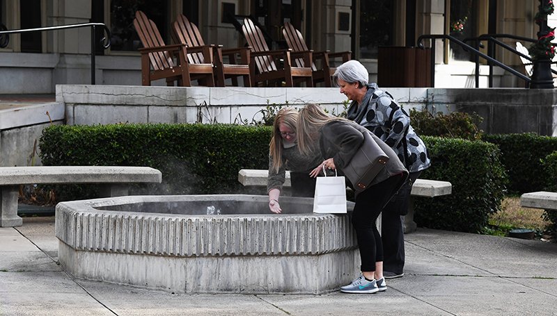 The Sentinel-Record/Grace Brown TESTING THE WATERS: Three women dip their fingers into a thermal fountain on Bathhouse Row between the Maurice and Fordyce bath houses in Hot Springs National Park on Thursday.