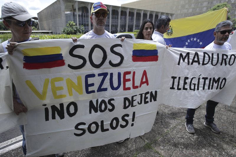 Venezuelan citizens living in Brazil hold signs that read in Spanish &quot;S.O.S. Venezuela. Don't leave us alone,&quot; left, and &quot;Maduro. Illegitimate,&quot; during protest against the inauguration of Venezuela's President Nicolas Maduro outside Itamaraty Palace in Brasilia, Brazil, Thursday, Jan. 10, 2019. Maduro started a second, six-year term Thursday despite international cries urging him to step down and return democratic rule to a country suffering a historic economic implosion. (AP Photo/Eraldo Peres)