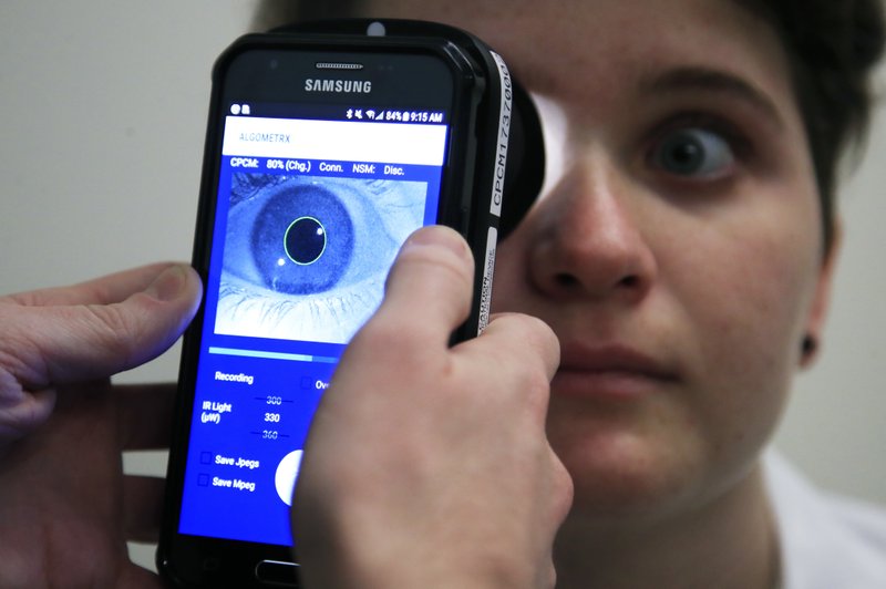 Clinical Research Assistant Kevin Jackson uses AlgometRx Platform Technology on Sarah Taylor's eyes to measure her degree of pain at the Children's National Medical Center in Washington, Monday, Dec. 10, 2018. Children's National Medical Center is testing an experimental device that aims to measure pain according to how pupils react to certain stimuli. (AP Photo/Manuel Balce Ceneta)