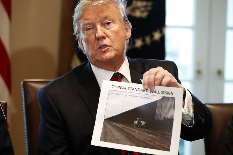 President Donald Trump holds a photo of a wall design Friday as he leads a discussion on border security in the Cabinet Room of the White House.