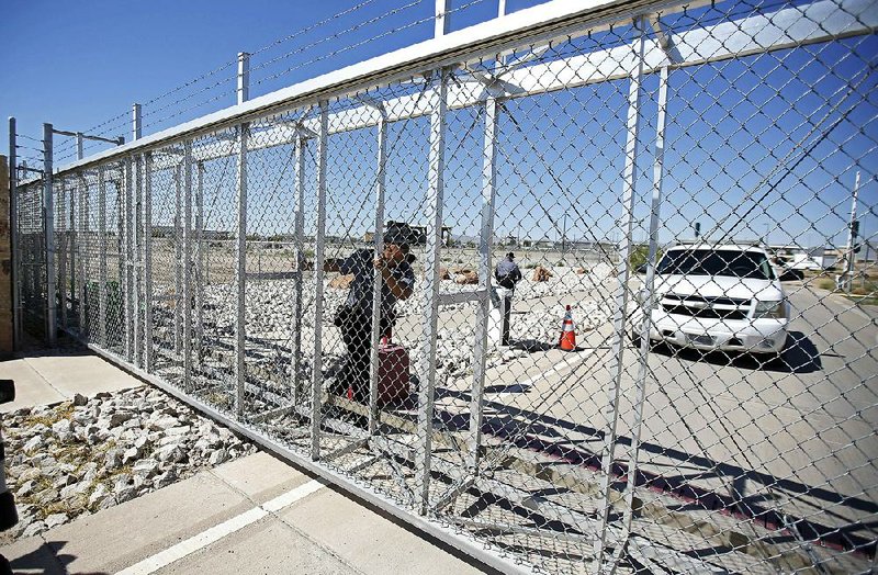 A June 21 photo shows an agent with the Department of Homeland Security closing the exterior gate of the holding facility for migrant children in Tornillo, Texas, near the Mexico border. The nonprofit operating the camp for migrant children confirmed it was closing and the last children left Friday. 