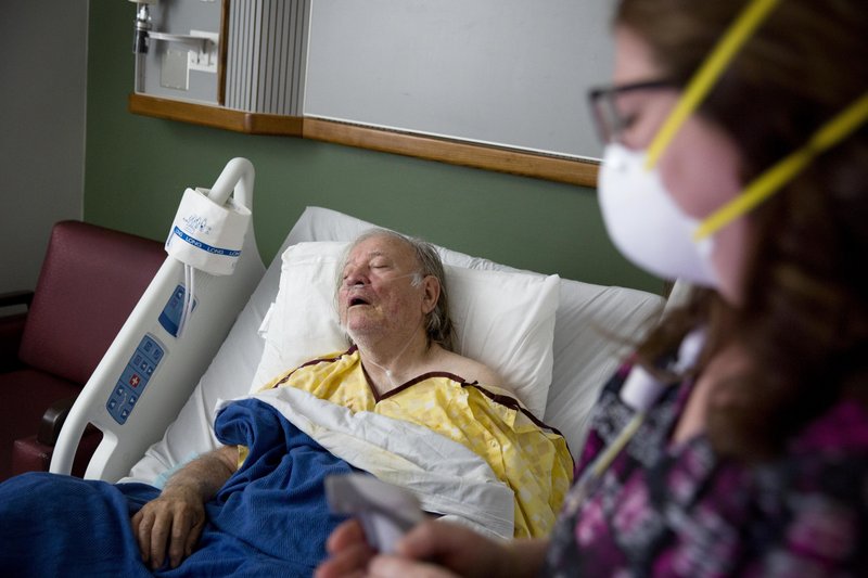 FILE - In this Friday, Feb. 9, 2018 file photo, Henry Beverly, 73, battles the flu while tended to by nurse Kathleen Burks at Upson Regional Medical Center in Thomaston, Ga. As of January 2019, the current flu season is shaping up to be gentler than last winter&#x2019;s unusually brutal one, health officials say. (AP Photo/David Goldman)