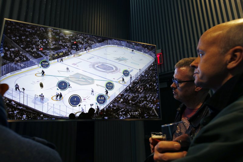 People watch real-time puck and player tracking technology on display during an NHL hockey game between the Vegas Golden Knights and the San Jose Sharks, in Las Vegas, Thursday, Jan. 10, 2019. (AP Photo/John Locher)